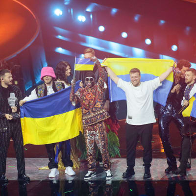 Kalush Orchestra poserar med Ukrainas flagga på Eurovisionsscenen.