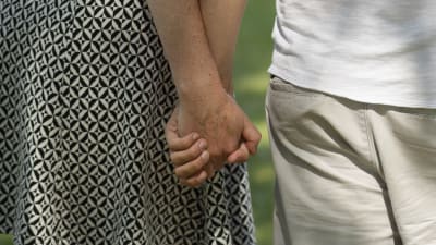 Mies ja nainen pitävät toisiaan kädestä