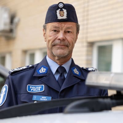 EN polis ser in i kameran. I förgrunden en polisbil. 