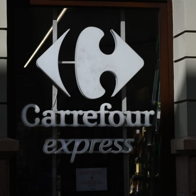 En vit skylt med en logo och texten "Carrefour express". Bakgrunden är mörk.
