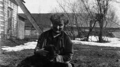 Edith Södergran sittande på marken med hund i famnen.