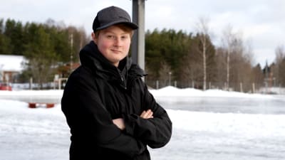 Eleven Sebastian Björkholm står utomhus. Han är vit, har mörka ögon, är klädd i svart och har en grå keps på huvudet. Han står med korsade armar och ler mot kameran.