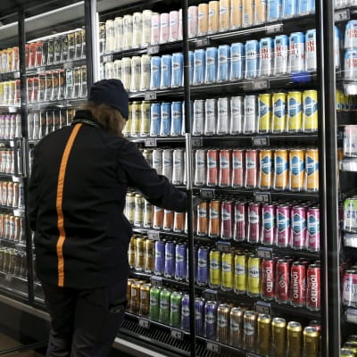 En man står vid ett kylskåp fullt av alkoholdrycker i en mataffär.