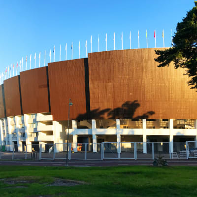 En sida av Olympiastadion med blå himmel.