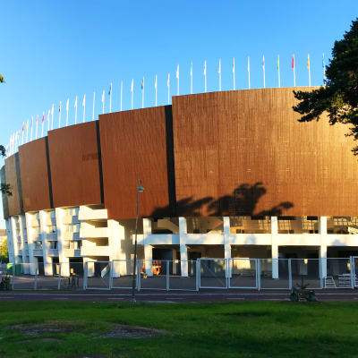 En sida av Olympiastadion med blå himmel.