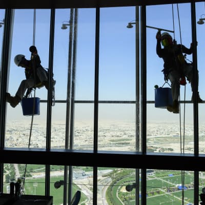Två migrant arbetare tvättar fönster i Aspire Tower som är en av de högsta byggnaderna i Qatar.