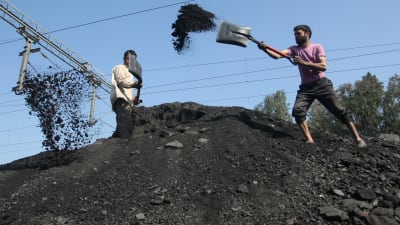 Indiska arbetare lastar kol på lastbilar.