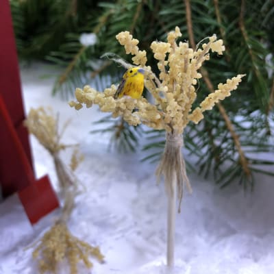 En julkärve i miniatyr i vilken det sitter en gulsparv i miniatyr.