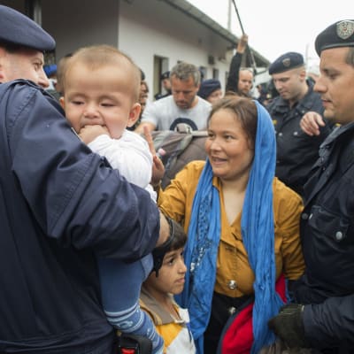 Österrikiska poliser hjälper mamma och barn att gå ombord på ett tåg på väg från byn Nickelsdorf till huvudstaden Wien den 5 september 2015.