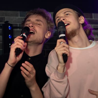 Olavi Tanttu ja Arttu Porkka laulavat karaokea yhdessä. Ilmeet ovat voimakkaasti lauluun eläytyvät.