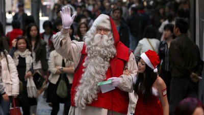 En finländsk julgubbe i Hongkong vinkar med handen.