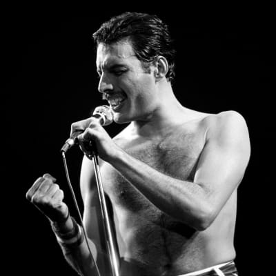 En man med knuten näve sjunger i en mikrofon på en svartvit bild.