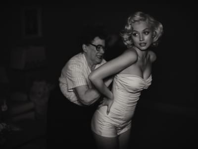 Svartvit bild där Marilyn Monroe (Ana de Armas) får hjälp med att snöra fast en korsett. 