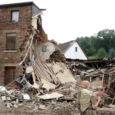 En man och en kvinna utanför ett totalförstört hus i Tyskland.