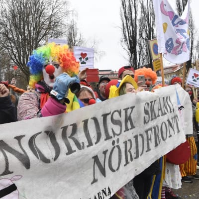 Motdemonstranter utklädda till clowner håller stor banderoll där det står "Nordisk skam! Nördfront"