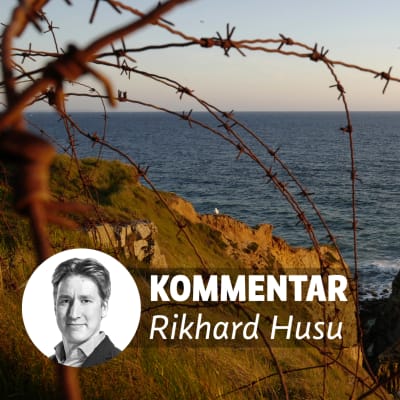 Taggtråd ligger på klippor vid stranden. På bilden en banner med texten "Kommentar Rikhard Husu".