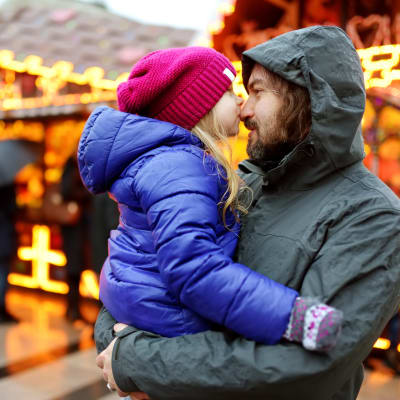 Pappa med liten flicka in famnen på en julmarknad