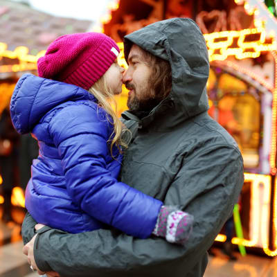 Pappa med liten flicka in famnen på en julmarknad