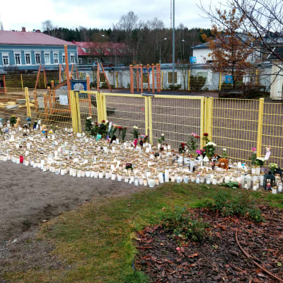 massor av gravljus, kramdjur och blommor framför lekparken i lyceiparken.