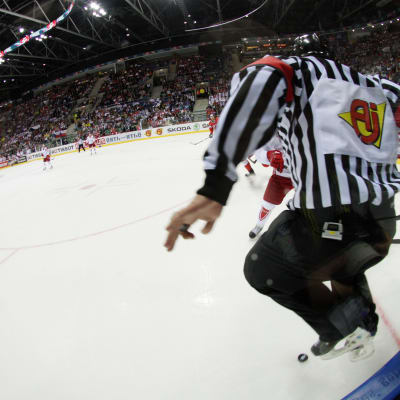 En ishockeydomare hoppar för att akta sig för pucken.