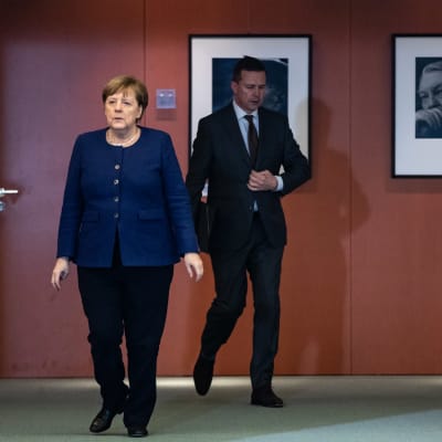 Angela Merkel ja Steffen Seibert kävelevät lehdistötilaisuuteen Saksassa maaliskuussa.