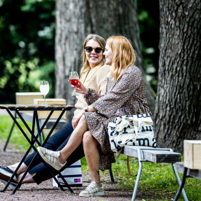 Två kvinnor sitter på en uteservering. 