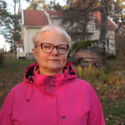 Eija Lamsijärvi står på gården utanför sitt hus