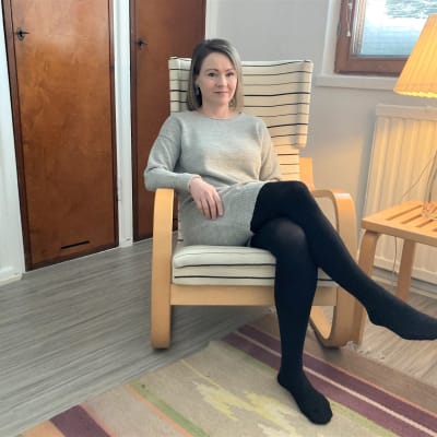 Nainen istuu Alvar Aallon suunnittelemassa nojatuolissa. 