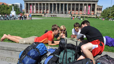 Fyra tågluffare ligger på gräsmattan i Lustgarten park i Berlin. 