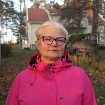 Eija Lamsijärvi står på gården utanför sitt hus