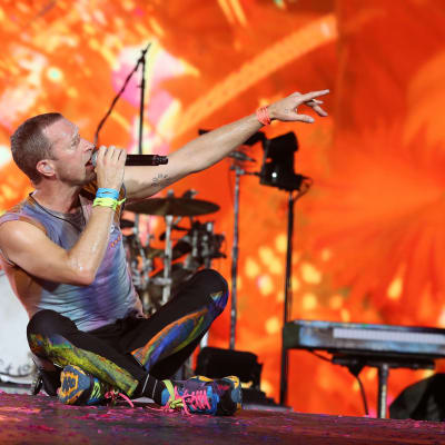 Coldplays sångare Christ Martin sitter på scenen under en konsert i Milano i juni 2023.