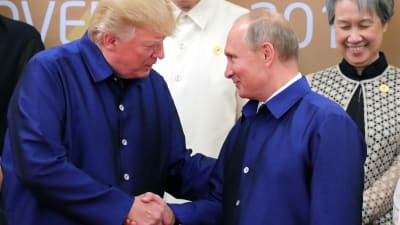 Donald Trump och Vladimir Putin skakar hand.