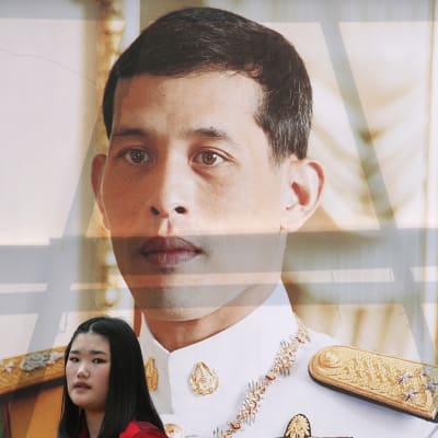 En student passerar förbi kungens porträtt i Bangkok