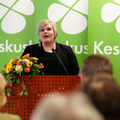 Annika Saarikko håller tal på Centern partifullmäktige. I bakgrunden Centerns logotyp.