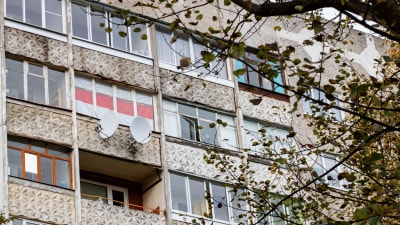 Den gamla belarusiska flaggan i vitt och rött hänger i ett fönster i ett höghus.