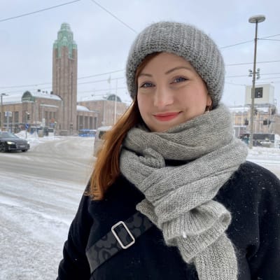 Hanna Hannus står på Brunnsgatan och tittar in i kameran. Det är vinter och järnvägsstationen syns i bakgrunden. 