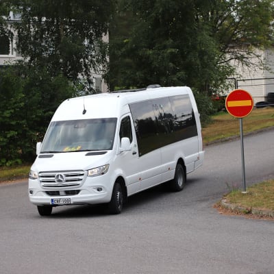 Koulukuljetuksessa oleva taksi ajamassa koulun pihaan.