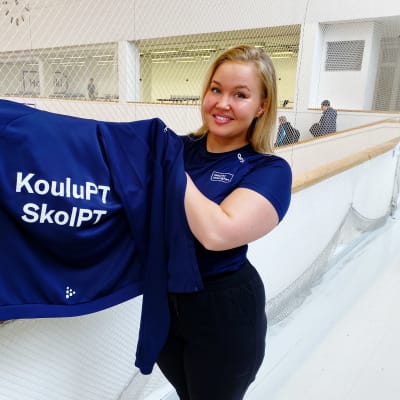 Jonna Kotivesi håller upp en collegetröja med texten skol-PT.