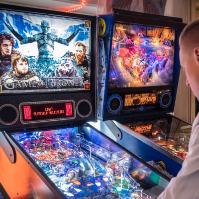 Profiilissa mies, pelaa flipperiä flipperihallissa, flipperissä lukee Game of Thrones