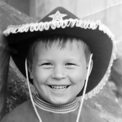 Viisivuotias Kimmo Helistö lännenhattu päässään katsoo kameraan ja nauraa.