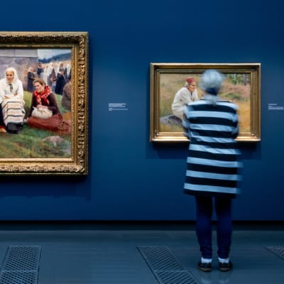 Raitapaitainen henkilö katsoo Albert Edelfeltin maalausta Ateneumin Taidemuseon näyttelyssä.