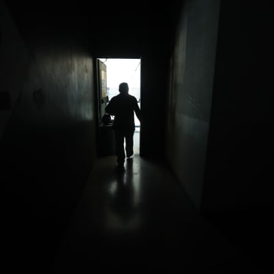 En man går i en mörk korridor i ett Caracas som är mörkt på grund av strömavbrott.