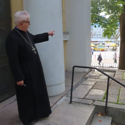 Turun ortodoksisen seurakunnan kirkkoherra osoittelee toria kirkon portailta.