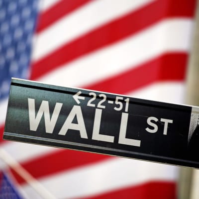 Wall Street-skylt framför USA:s flagga.