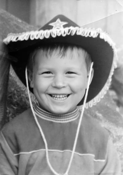 Viisivuotias Kimmo Helistö lännenhattu päässään katsoo kameraan ja nauraa.