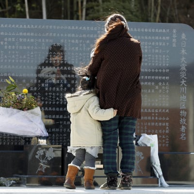 En sörjande mamma med sin dotter vid ett minnesplakat för de som omkom i katastrofen.