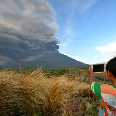 En pojke fotograferar rökmolnet från vulkanen Agung i Kubu, Bali, den 26 november. 