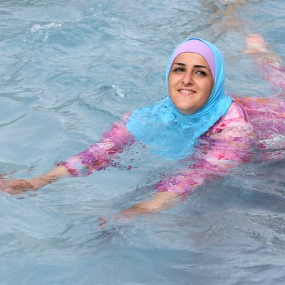 En turkisk ung kvinna simmar iklädd täckande burkini.