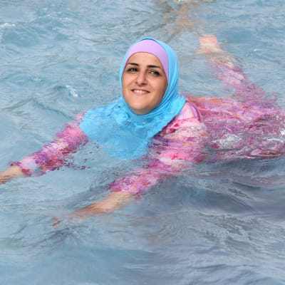 En turkisk ung kvinna simmar iklädd täckande burkini.