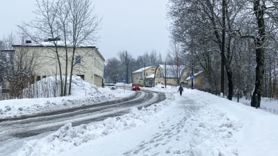 Vy mot centrum av Lappträsk. Någon går på en gångväg och en bil kommer emot. Det är snö och slask på marken.